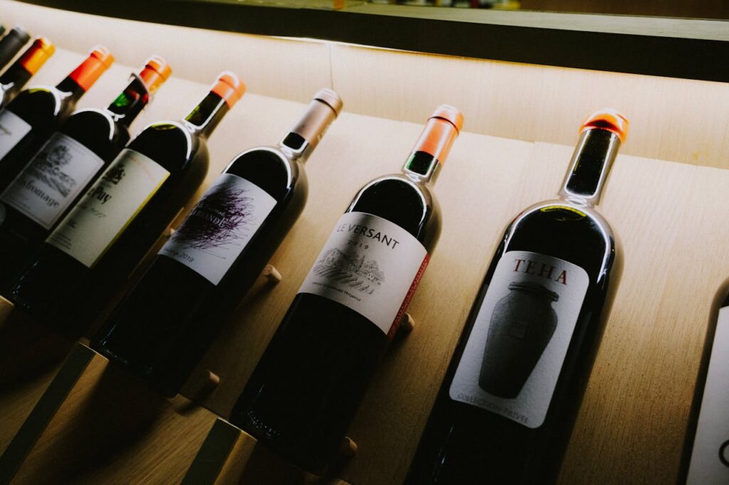 pexels-photo-11739092 Close-up view of assorted wine bottles on a stylish wooden display shelf.